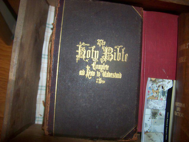 A bible is sitting on top of some other books.