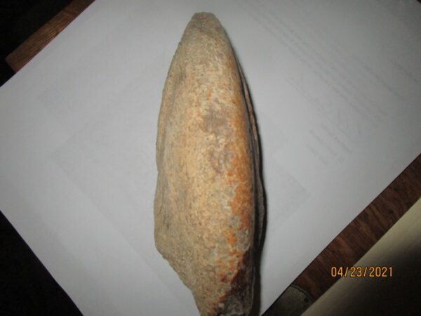 A stone axe sitting on top of a white paper.
