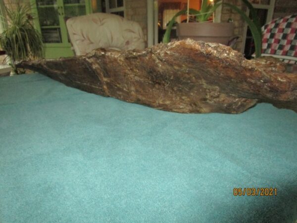 A bed with blue sheets and a large piece of wood.